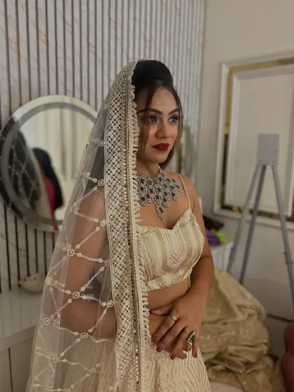 A close-up shot of a model wearing the ivory chikankari lehenga, with the sheer dupatta draped over her head for a classic look.