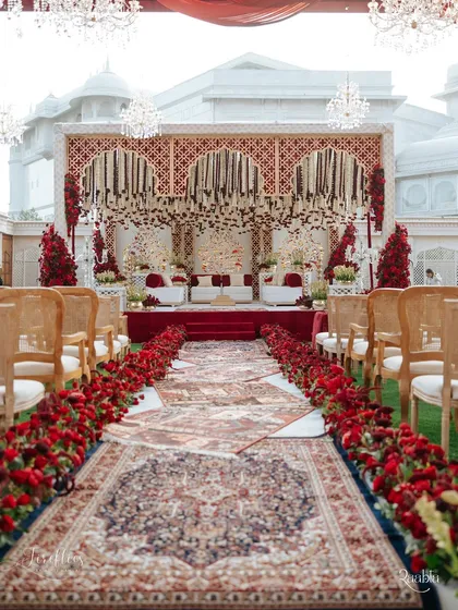 The aisle for Naomi and Rakshit's 'Laal Ishq' wedding, leading to a magnificent mandap. We used a series of ornate Persian rugs for the walkway, bordered by a dense arrangement of red roses, setting a regal tone for the ceremony.