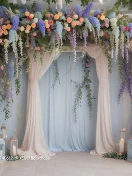 I can bring fairytale wedding themes to life. This backdrop uses a mix of pastel flowers like roses and wisteria with hanging greenery to create an enchanting, garden-like setting.