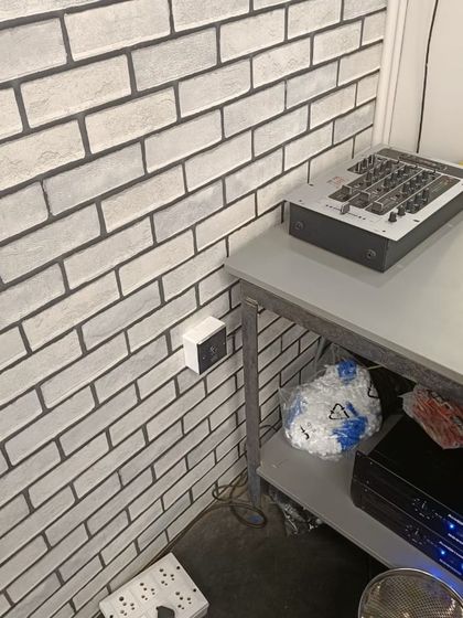 The exit button for the gym's access control system, installed on a modern brick-patterned wall next to the DJ console.