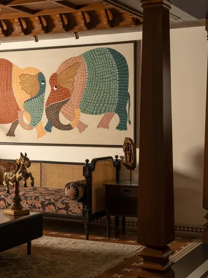 The living area, where a massive Gond art piece depicting two elephants becomes the heart of the room. The furniture, a mix of antique and modern forms, is arranged to facilitate conversation and appreciation of the art.