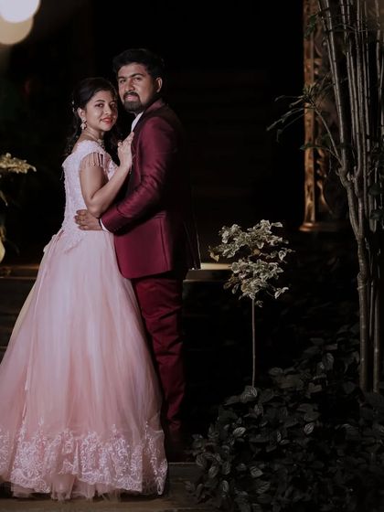 A romantic nighttime shot of a couple. The client is wearing a delicate peach ball gown, which pairs beautifully with her partner's maroon suit for an elegant evening look.