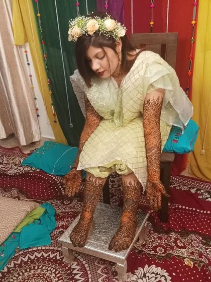 A candid moment with a bride showcasing her full hand and feet mehndi. The design is traditional and provides heavy coverage, perfect for a classic bridal look.