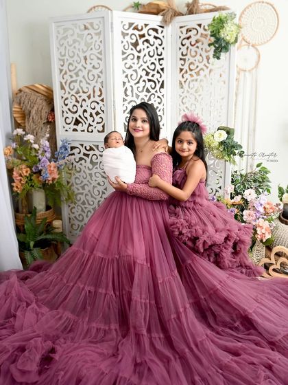 A mother's love for her two children. She holds her newborn son while her daughter embraces them both, all dressed in stunning matching purple gowns.
