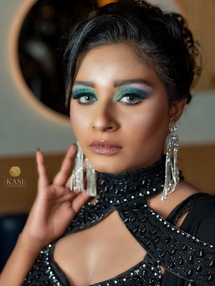 A close-up of a glamorous black-on-black look. The pop of blue-green glitter on the eyes is the star.