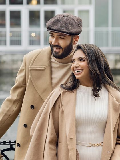 Sharing a happy moment by the water. Their matching camel coats and vintage-inspired styling create a timeless and sophisticated look for their pre-wedding shoot.