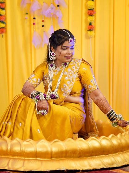 The bride is seated in a decorative tub for her Haldi ceremony. Her hairstyle is both beautiful and practical for the rituals.