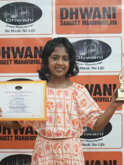 A smiling student proudly displays her certificate and award for her artistic talents.