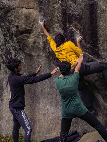 The perfect example of spotting technique. Three spotters create a safe zone for the climber, allowing her to commit to the move with confidence. This is a core part of our outdoor bouldering clinics.