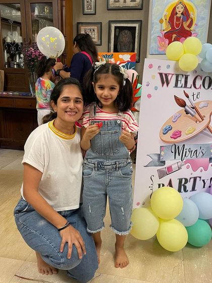 A happy moment with the birthday girl at her art-themed party. Her overalls and bare feet show she was ready for some serious creative fun!