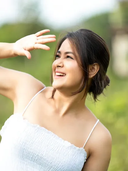 A sunny, happy shot where the model is shielding her eyes from the sun, creating a natural and spontaneous feel.