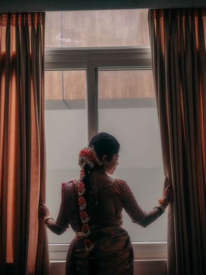 An artistic silhouette of the bride looking out the window, a moment of quiet contemplation before the ceremony.