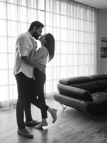 A classic, timeless moment captured in black and white. The soft light from the window and their gentle embrace create a feeling of pure romance. This kind of intimate portrait focuses solely on the emotion and connection between two people.