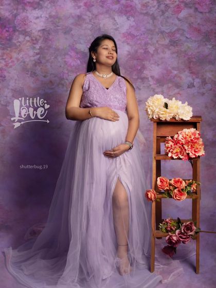 A serene solo portrait of an expecting mother in a beautiful lavender gown. Her peaceful expression and the gentle way she holds her bump convey a sense of calm and happy anticipation.