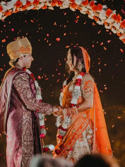 A beautiful moment during the varmala ceremony under a floral arch. I focus on creating stunning backdrops that make your wedding photos look like works of art.