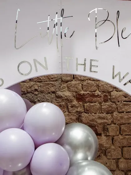 A close-up of the personalized backdrop with the message 'A Little Blessing is on the Way' in elegant silver script.