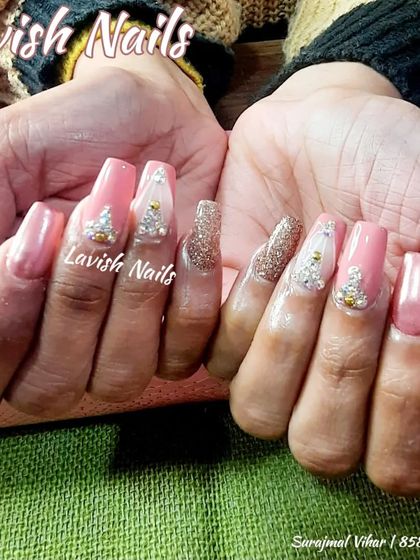 Long, pink coffin nails ready for a celebration, with gold glitter and charming Christmas tree rhinestone art.