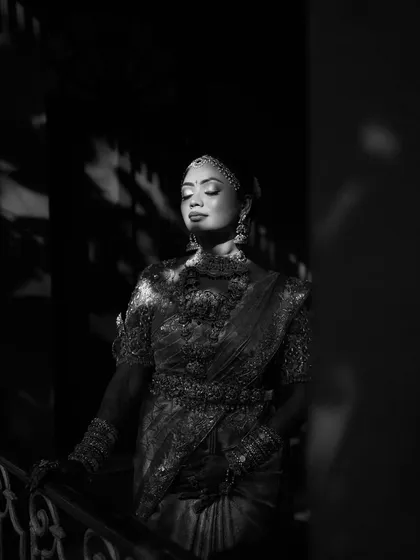 A black and white portrait of a bride, her face illuminated by a sliver of light, creating a dramatic and artistic effect.