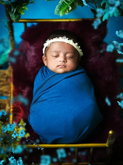 An overhead view of the newborn in the blue floral bed, framed by ethereal blue flowers and greenery, creating a beautiful and artistic composition.