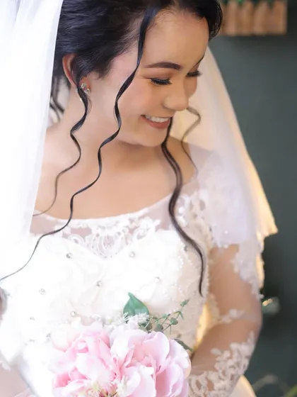 A beautiful, candid shot of the bride smiling. The soft curls framing her face and the delicate makeup create a look that is both romantic and effortlessly chic.