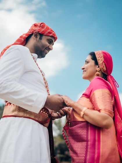 A low-angle shot of a couple holding hands against a bright blue sky, symbolizing their bright future together.