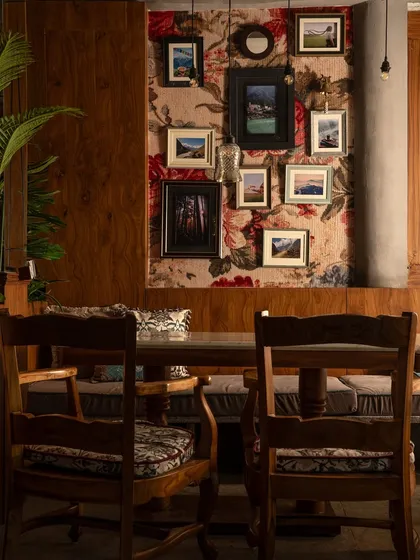 This dining nook at Echoes feels like a private corner in a mountain home. The floral wallpaper, gallery wall of landscape photos, and sturdy wooden furniture create a warm and inviting atmosphere for sharing a meal.