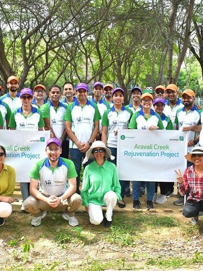 The enthusiastic team from Aramco poses for a group photo after their successful planting drive at Aravali Creek, celebrating their contribution to a greener city.