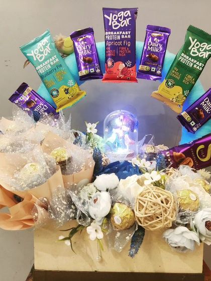 A unique anniversary hamper featuring a chocolate bouquet of Ferrero Rocher and a halo of Yoga Bars. The centerpiece is a beautiful snow globe, creating a magical and memorable gift.