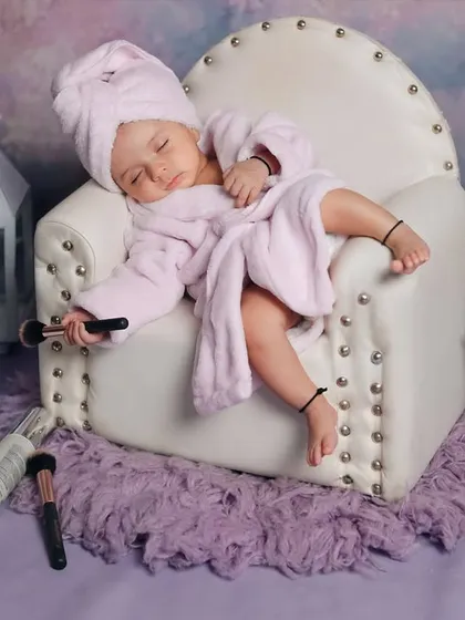 A wider shot of the hilarious 'Mini Spa Day' setup. The baby is completely relaxed, surrounded by all the essentials for a day of pampering.