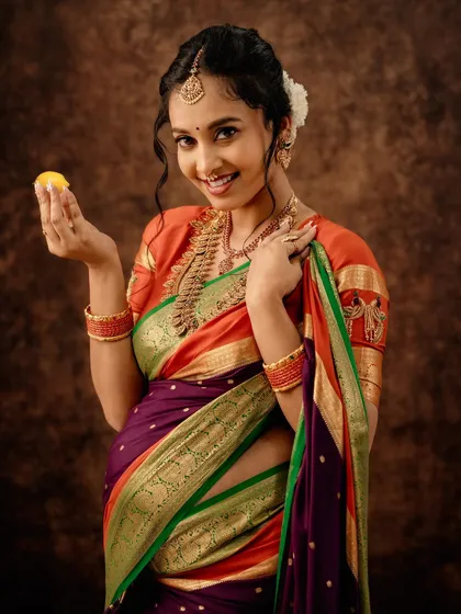 A joyful portrait of a mother-to-be in a beautiful multi-colored silk saree. The traditional jewelry, gajra, and playful expression capture the happiness of this journey.