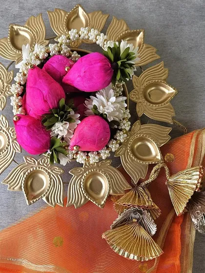 A beautiful flat-lay of a lotus urli diya platter, filled with decorative pink lotuses. This piece is perfect as a centerpiece or a standalone gift, bringing traditional beauty to any festive decor.