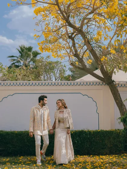 The couple walking through a garden with beautiful yellow-flowered trees. I scout for the most picturesque spots within a venue to ensure your wedding album is filled with diverse and stunning shots.