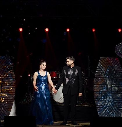 The couple on their Sangeet stage, which features modern, geometric backdrops and dramatic stage lighting for a contemporary and edgy feel.