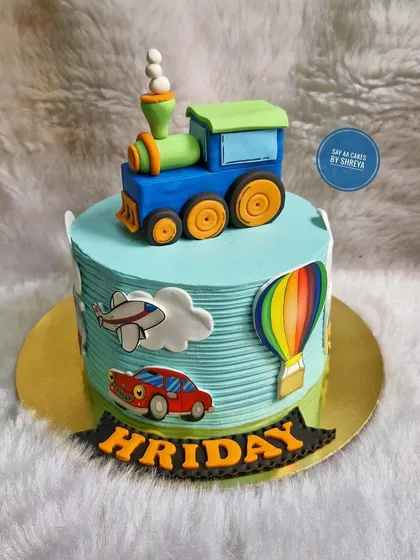 All aboard the birthday express! This cake features a sculpted fondant train engine on top, with a car, plane, and hot air balloon around the sides, perfect for a child fascinated by vehicles.