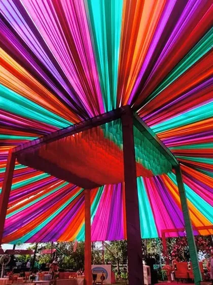 A vibrant canopy of colorful drapes creates a festive ceiling for this outdoor event. This is a great way to add a huge splash of color and create a carnival-like atmosphere.