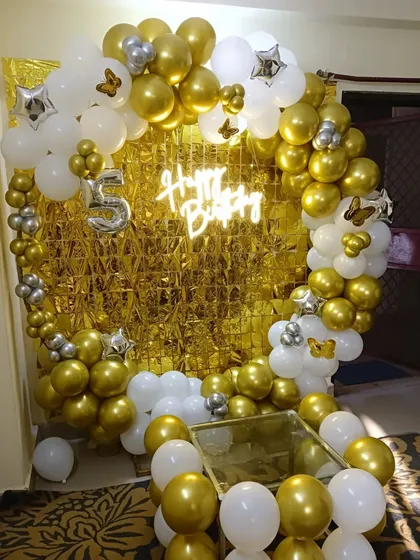 A classic and elegant theme for a 5th birthday using a gold and white color palette. This circular balloon arch with a neon sign and a number '5' foil balloon creates a stunning centerpiece for the celebration.