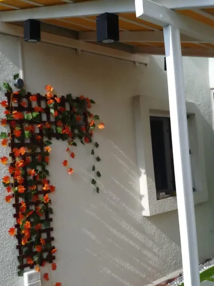 A different angle of the balcony, showing the artificial autumn-leaf creeper on a wooden trellis. This adds a pop of color and a touch of nature to the wall without requiring any maintenance.