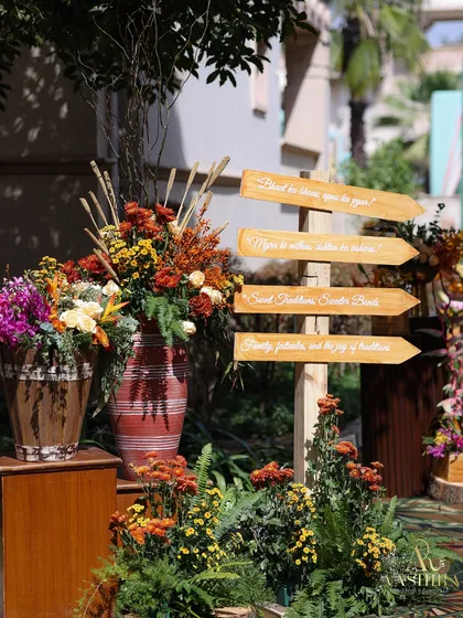 A charming wooden signpost to guide guests, surrounded by lush arrangements of tropical and rustic florals.