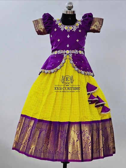A classic yellow and purple checked Pattu Pavadai. The peplum blouse has a velvet finish and delicate embroidery.