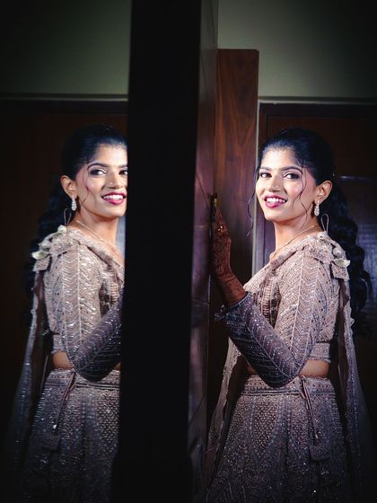 A creative shot of Sahana and her reflection, both smiling and looking beautiful on her special day.