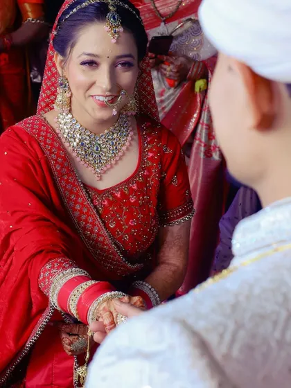 A close-up of the couple holding hands during a wedding ritual, capturing the bride's happy expression.
