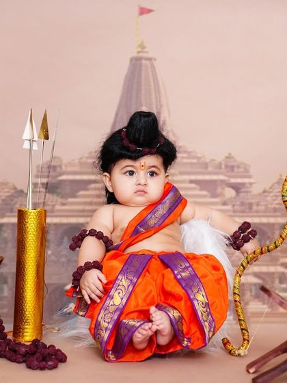 A majestic themed shoot with a baby dressed as Bala Rama, seated before a backdrop of the Ayodhya Ram Mandir.