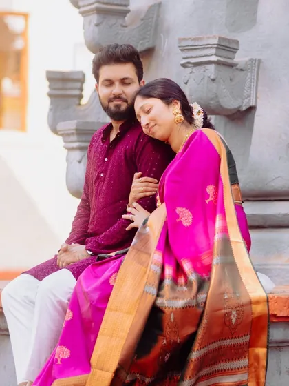 A tender moment during a pre-wedding shoot with a traditional theme. The couple's coordinated ethnic wear and the serene setting by a temple structure add a cultural touch to their love story.