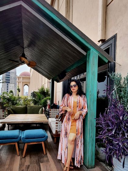 A vibrant look with an orange dress and a printed shrug, perfect for a rooftop lounge.