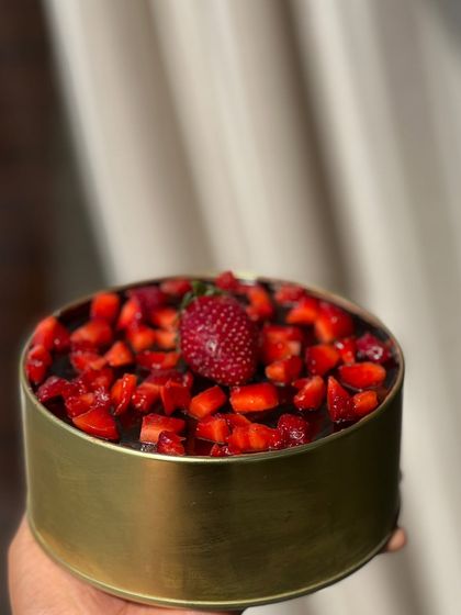 Our strawberry dream cake in a tin, topped with a single perfect strawberry. It's a beautiful and delicious personal-sized dessert.