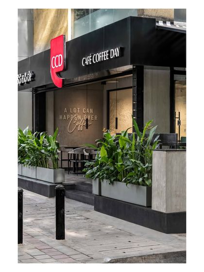 The refreshed facade blends timeless charm with a modern touch. The prominent red CCD logo contrasts with the sleek black storefront and the lush green planters, creating a memorable street presence.