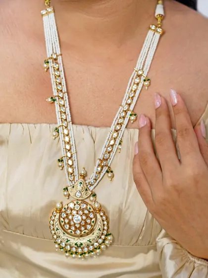 Another view of the stunning kundan rani haar with a large circular pendant. The intricate workmanship and use of pearls and green enamel make this a truly special piece.