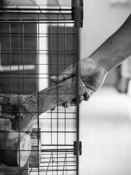 Getting the kitchen ready to bring you some epic pizzas. A hand reaches for a log to fuel the wood-fired oven.