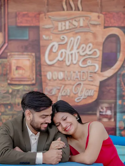 A playful moment sharing a drink against a vibrant blue door, reminiscent of a European street. The woman's bright red dress pops against the cool tones, creating a lively and stylish pre-wedding photo.