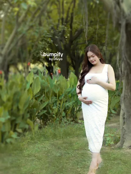 A serene portrait of the expecting mother walking through a garden. The soft focus on the lush greenery creates a dreamy backdrop for this beautiful solo maternity shot.